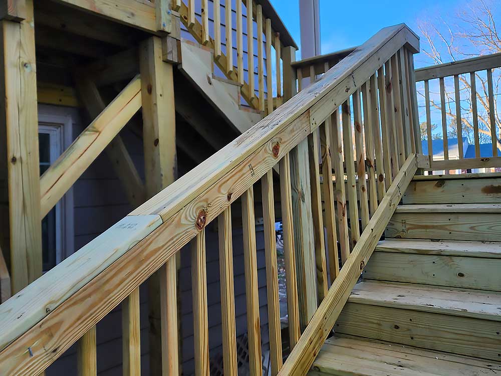 A newly constructed staircase made of pressure treated lumber showcases professional craftsmanship, ideal for custom decks and outdoor living. The light wood contrasts with a clear blue sky, highlighting a focus on high-quality, durable materials.| First In Decks and Fencing | Virginia Beach Deck Builders