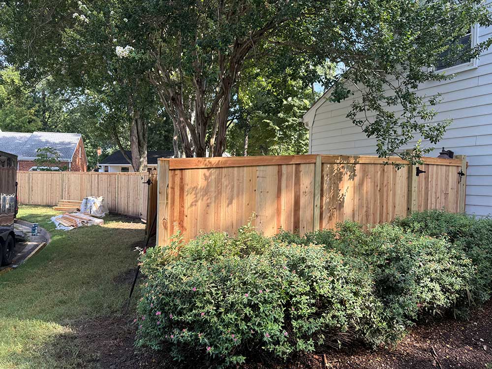 A newly installed wooden fence in a backyard, providing privacy and a touch of natural beauty, highlights professional craftsmanship and dependable service, ideal for outdoor living and home improvement in Norfolk.| First In Decks and Fencing | Virginia Beach Deck Builders