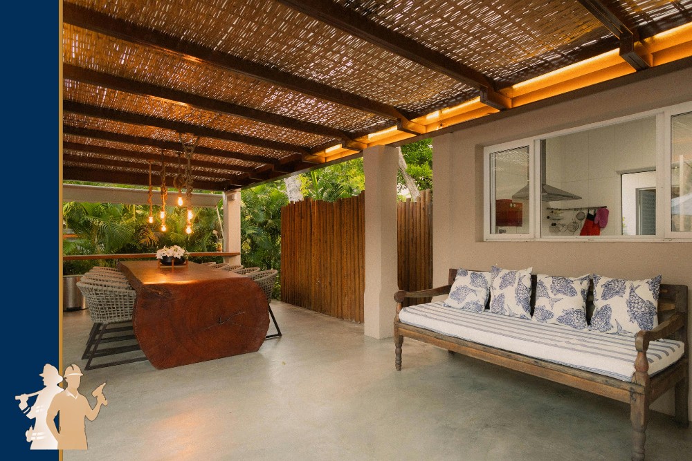 A cozy outdoor living space with a wooden pergola, featuring a rustic table, wicker chairs, and a cushioned bench, showcasing professional craftsmanship and high-quality materials, ideal for backyard transformation in Virginia Beach.| First In Decks and Fencing | Virginia Beach Deck Builders