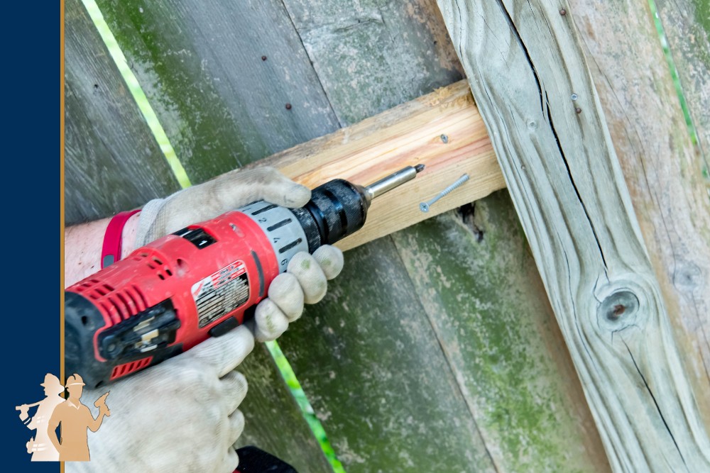 How to Protect Your Fence from Moisture-3 A person uses a red power drill to secure a wooden fence panel, showcasing professional craftsmanship and durable materials. This image highlights the process of fence installation, emphasizing high-quality home improvement services.| First In Decks and Fencing | Virginia Beach Deck Builders